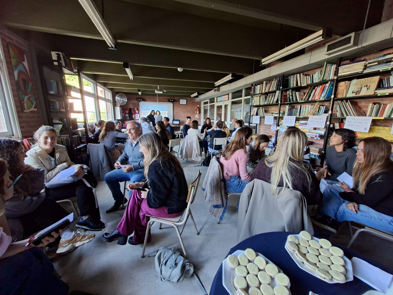 Padres y madres reunidos en un taller para familias en la biblioteca del Colegio San Javier