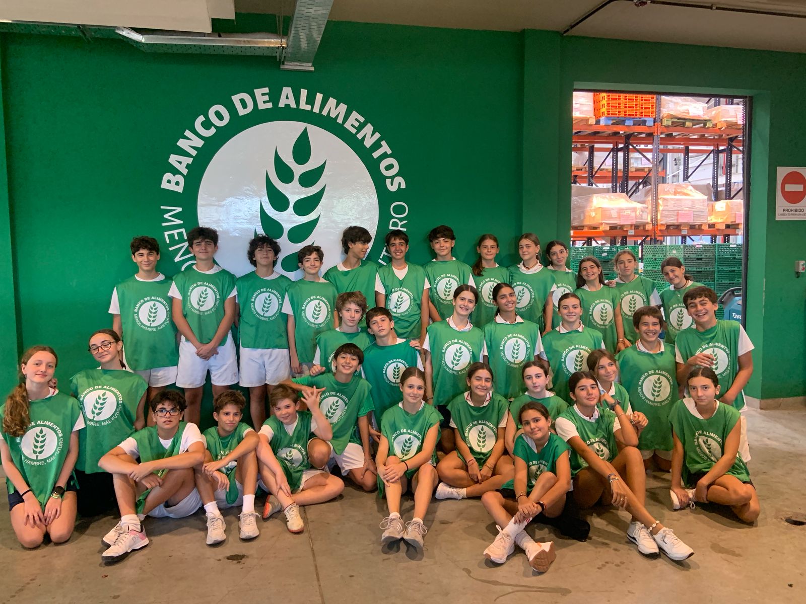 Alumnos secundarios del Colegio San Javier con remeras verdes haciendo voluntariado en el Banco de Alimentos