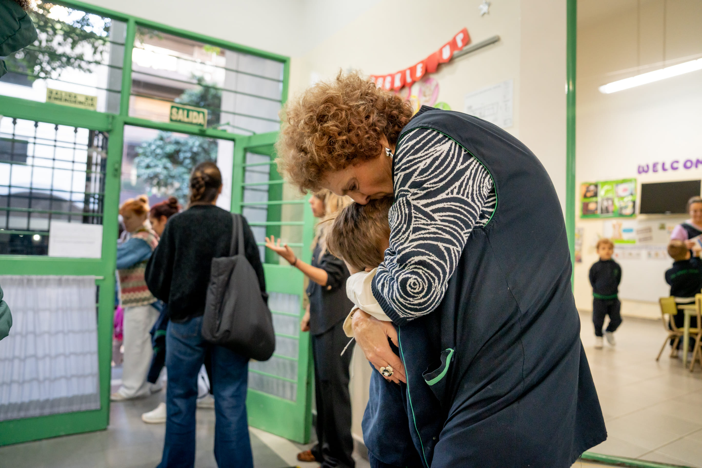 Directora recibiendo con un abrazo a un alumno en la entrada de The Green House Kindergarten
