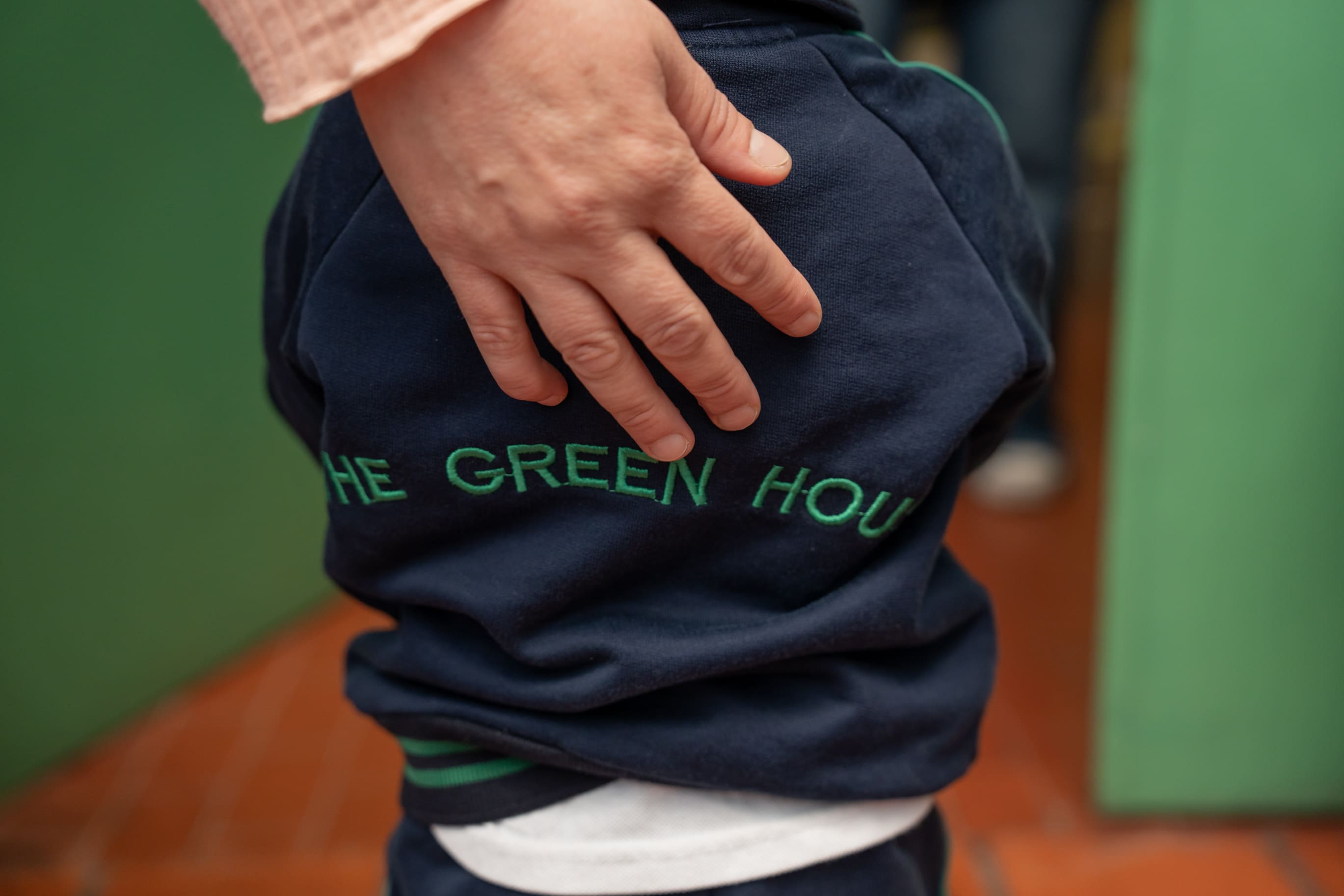 Maestra apoyando la mano en la espalda de un alumno con el uniforme de The Green House Kindergarten