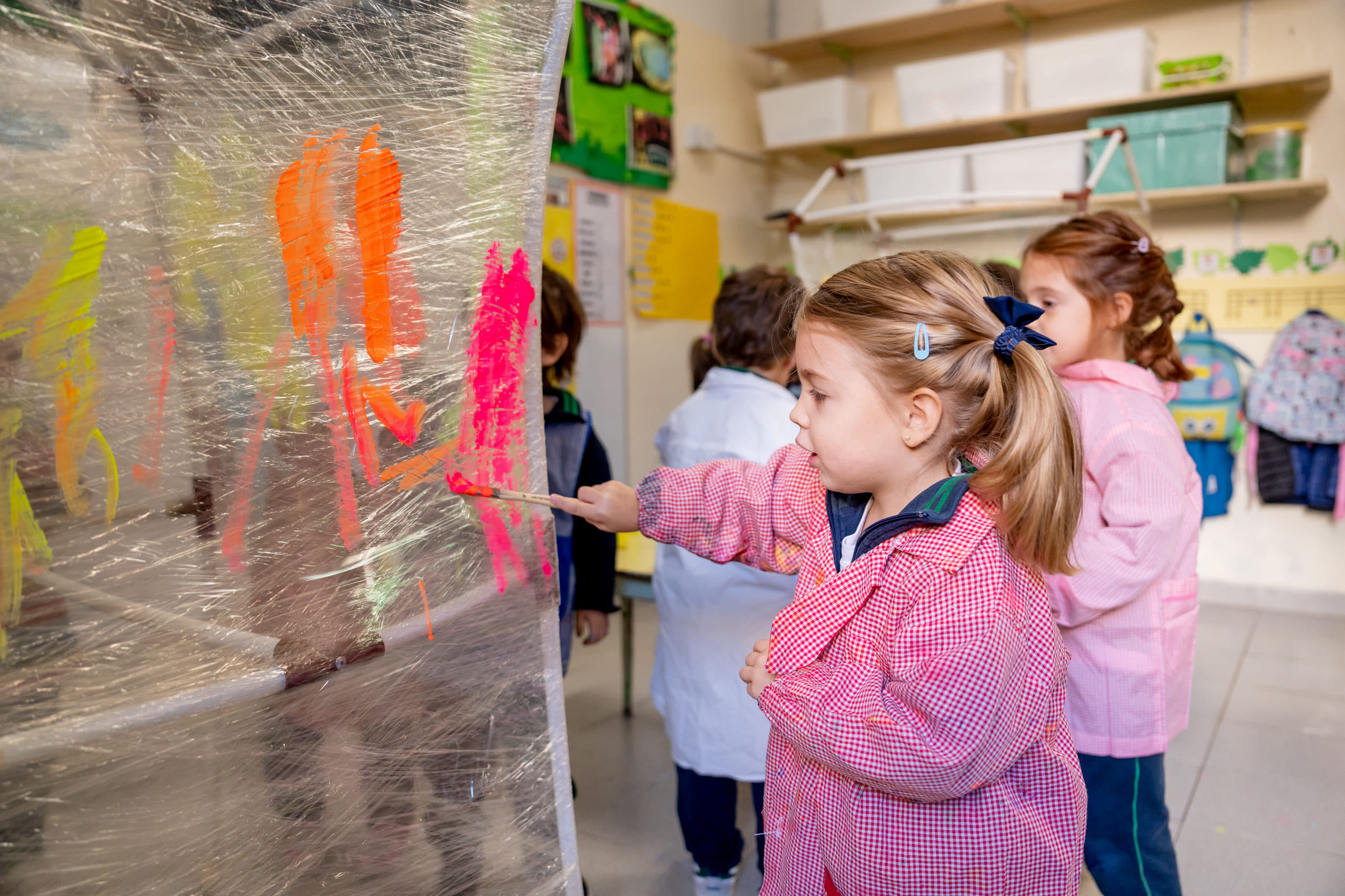 Nena pintando un mural grupal con pincel en el aula de The Green House Kindergarten