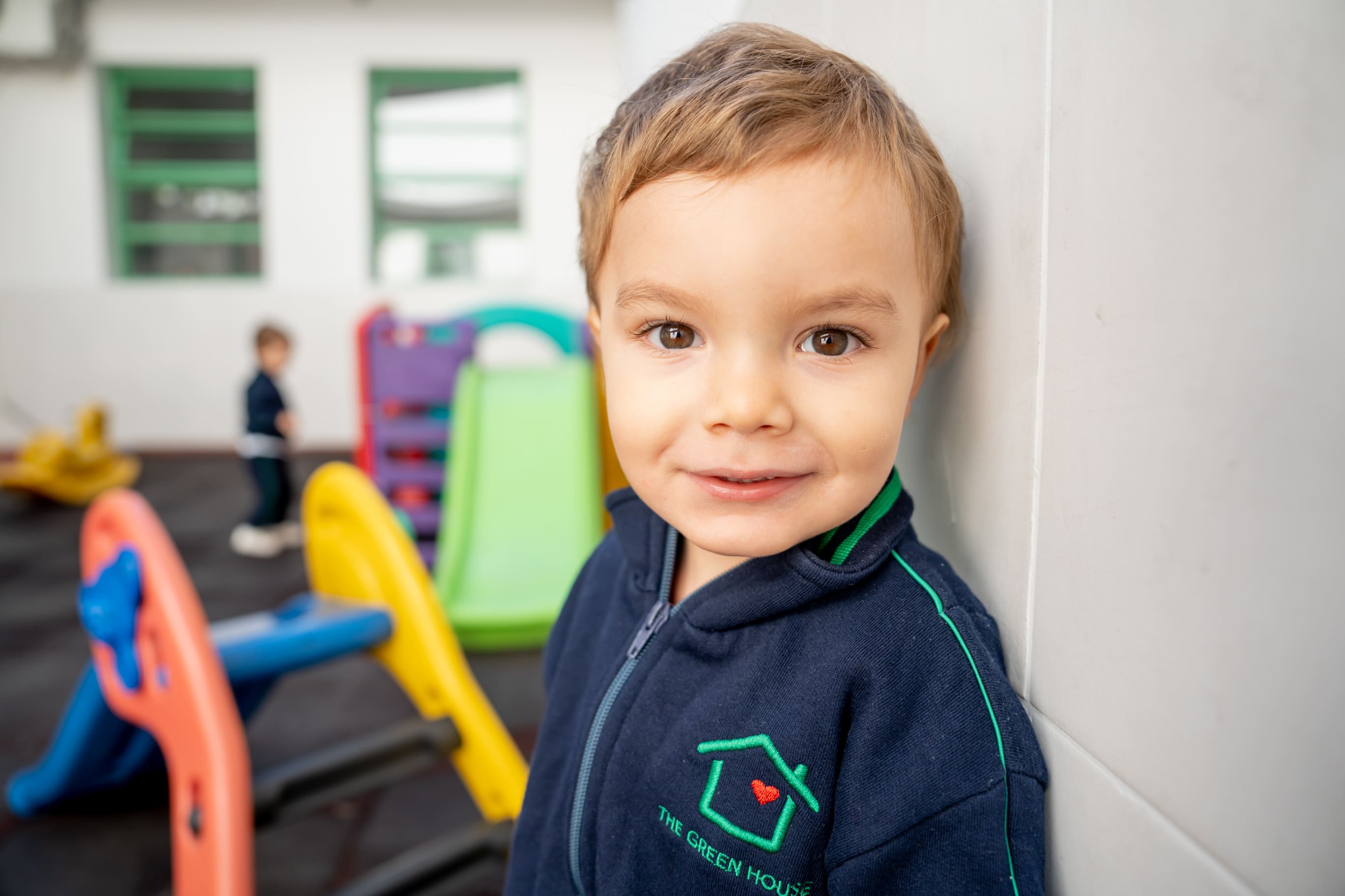 Nene del jardín de infantes sonriendo junto a los toboganes del patio de The Green House Kindergarten