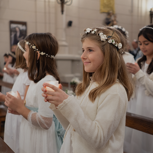 Alumna con corona de flores sosteniendo una vela durante la ceremonia de Primera Comunión en la capilla del Colegio San Javier