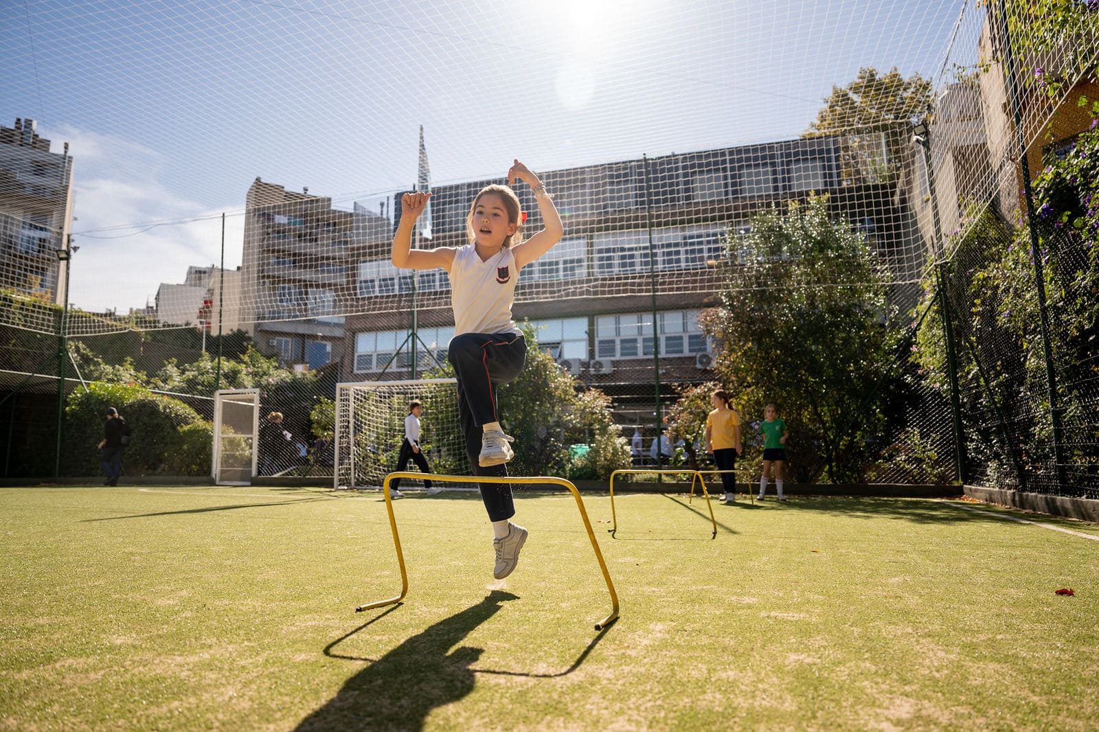 Alumna de primaria saltando una valla de atletismo en el patio deportivo del Colegio San Javier