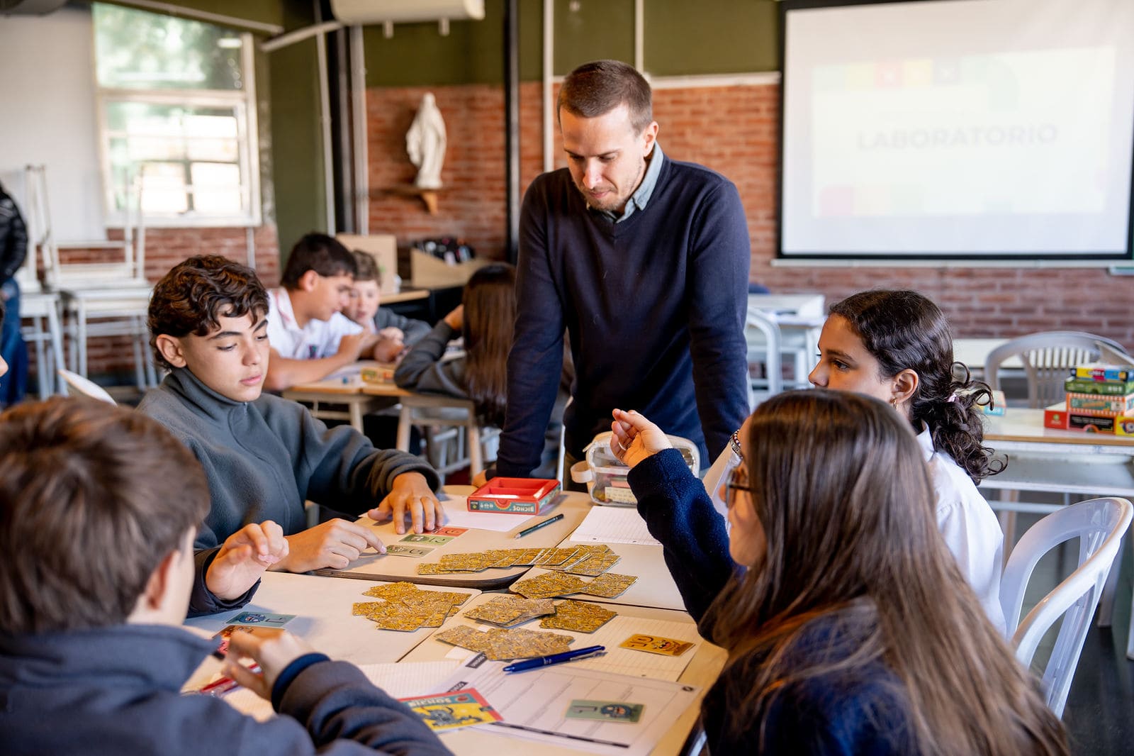 Profesor secundario junto a alumnos trabajando con tarjetas en una actividad grupal en el aula del Colegio San Javier