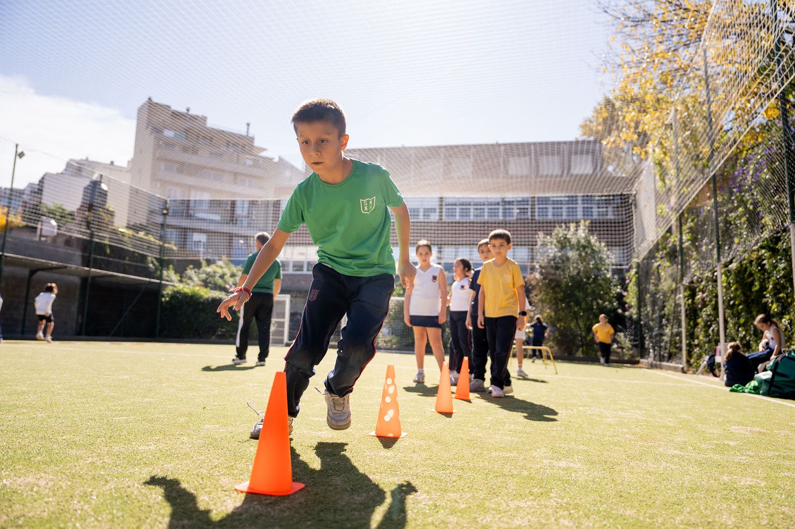 Alumno de primaria esquivando conos en un ejercicio de velocidad en la cancha del Colegio San Javier