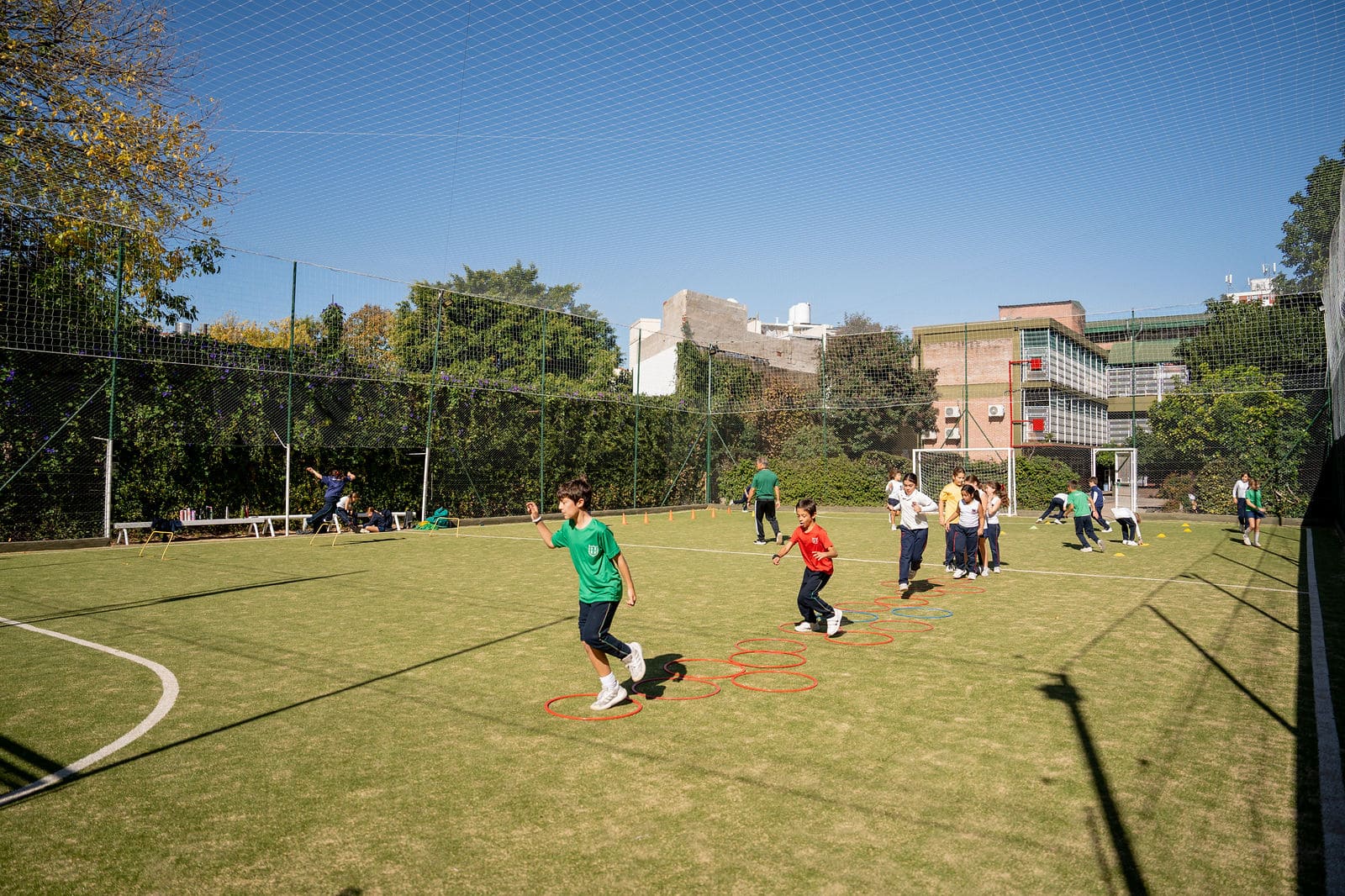 Alumnos de primaria corriendo entre aros de agilidad en la cancha de fútbol del Colegio San Javier