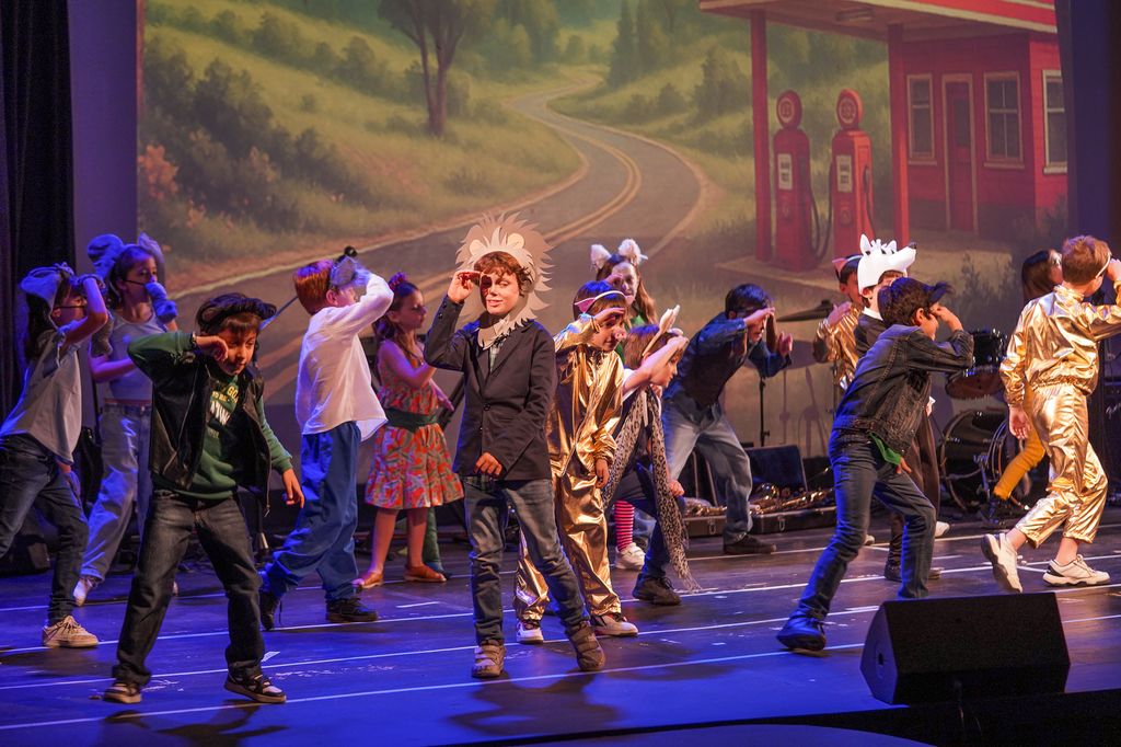Alumnos secundarios del Drama Club bailando disfrazados en el escenario del Colegio San Javier